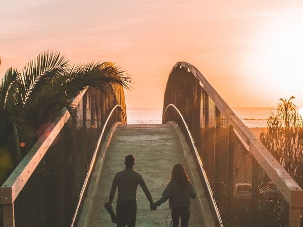 Ein Paar läuft über eine Brücke in Richtung Sonnenuntergang.